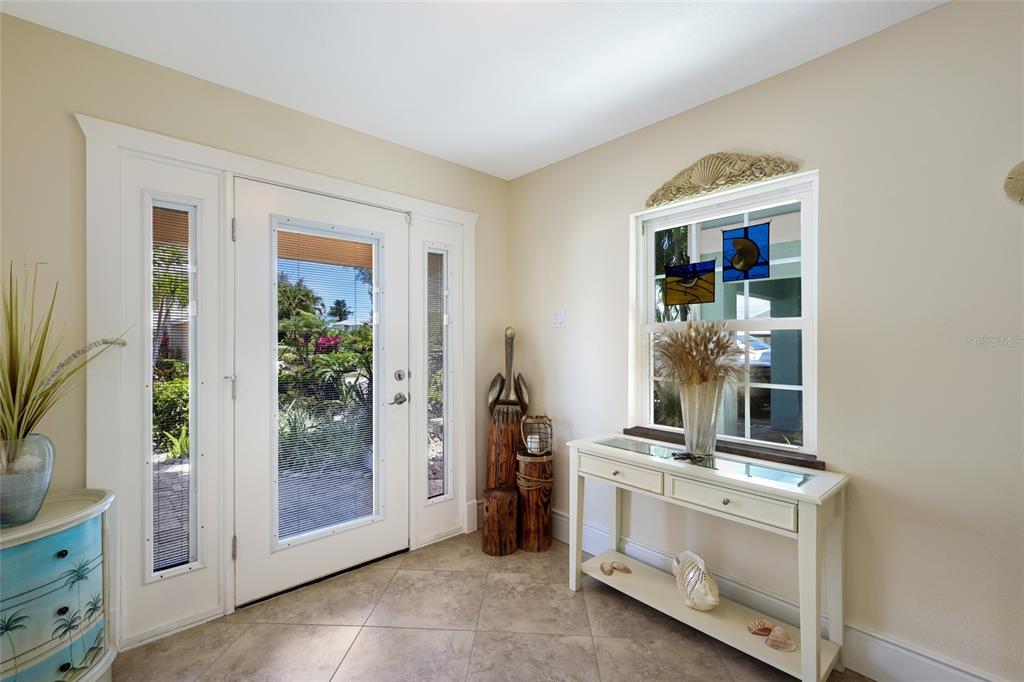An entryway features a white front door with sidelights, tile flooring, and a console table — 309 68TH STREET, HOLMES BEACH, FL