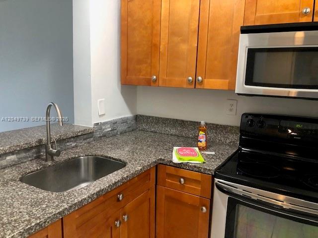 A kitchen features wood cabinets, granite countertops, a stainless steel sink, and a microwave — 498 NW 165th St Rd # 304, Miami FL 33169, MIAMI, FL