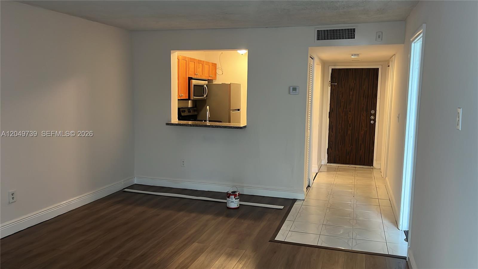 An interior view shows a living area with wood-look flooring, a kitchen pass-through, and tiled entryway — 498 NW 165th St Rd # 304, Miami FL 33169, MIAMI, FL