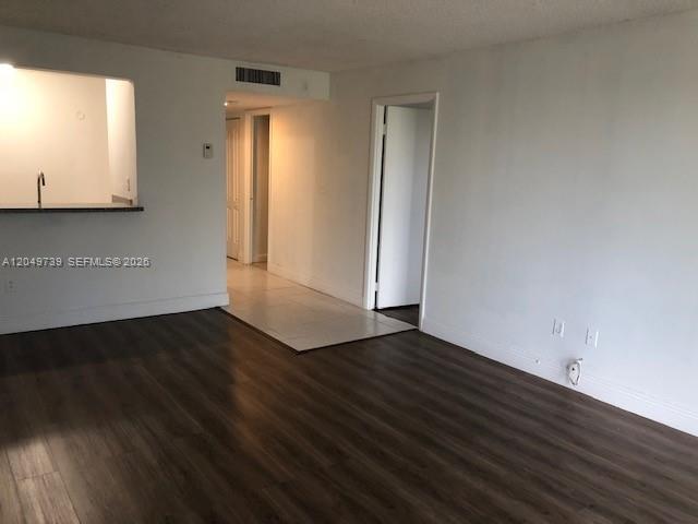 An interior view of a room with dark wood-look flooring and a kitchen pass-through window — 498 NW 165th St Rd # 304, Miami FL 33169, MIAMI, FL