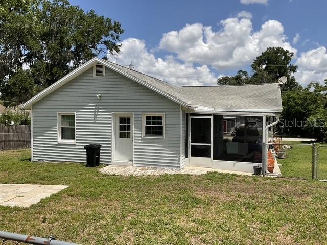 The exterior of a light-colored, single-story house features a screened-in porch and a fenced yard — 37204 MAGNOLIA AVENUE, DADE CITY, FL