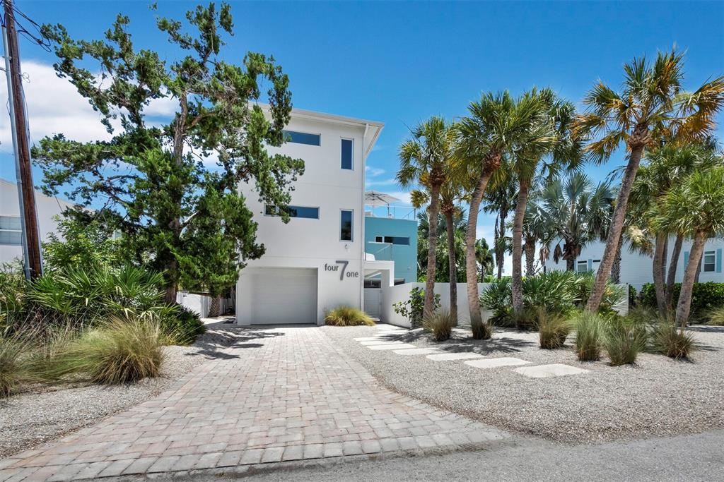 A modern white three-story house with a garage and palm trees in the front yard — 471 ISLAND CIRCLE, SARASOTA, FL