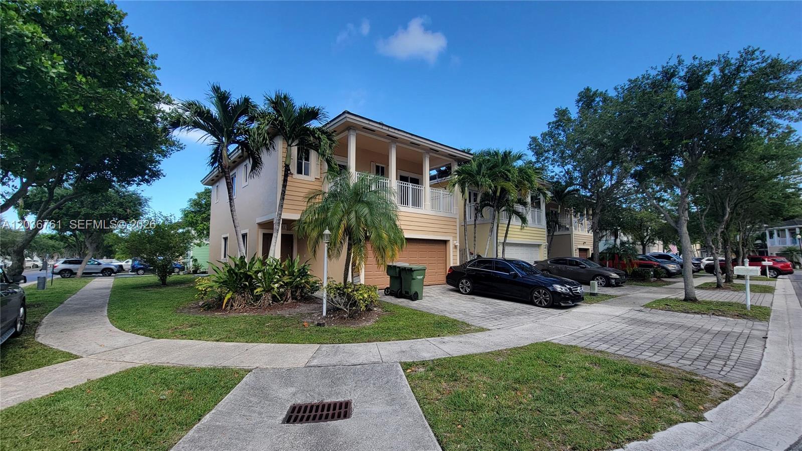 A two-story suburban house with a tan exterior, a garage, and a paved driveway — 391 NE 33rd Ter, Homestead FL 33033, HOMESTEAD, FL