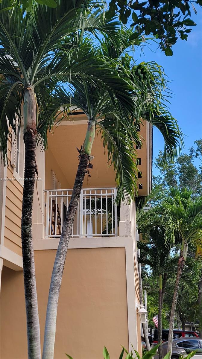 A tan building exterior features a second-story balcony with a white railing and palm trees — 391 NE 33rd Ter, Homestead FL 33033, HOMESTEAD, FL