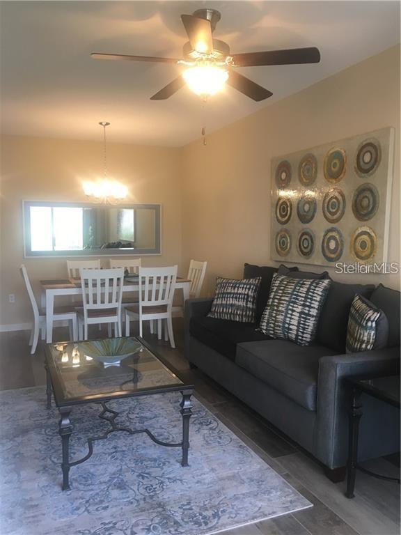 A living room and dining area feature a dark sofa, glass coffee table, and chairs — 1231 GODAVARI WAY UNIT 103, WESLEY CHAPEL, FL