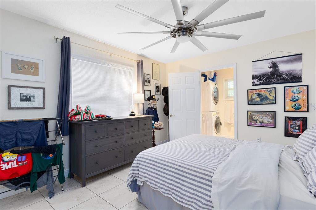 A bedroom features a gray dresser, a striped bed, a ceiling fan, and wall art — 607-609 CALIFORNIA AVENUE, ST CLOUD, FL