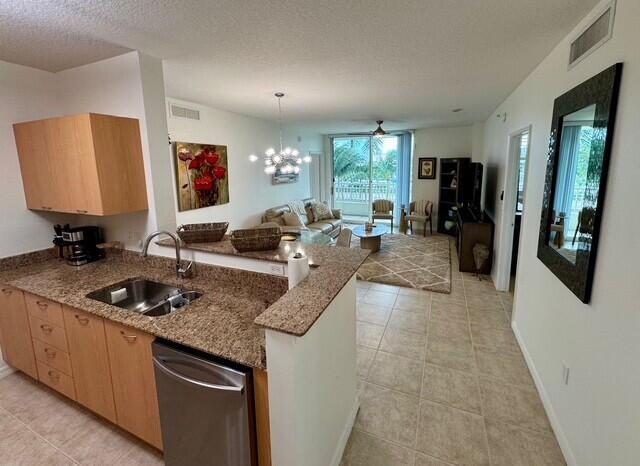 A kitchen with granite countertops and light wood cabinets overlooks an open-concept living area — 625 Casa Loma Boulevard # 304, Boynton Beach FL 33435, BOYNTON BEACH, FL