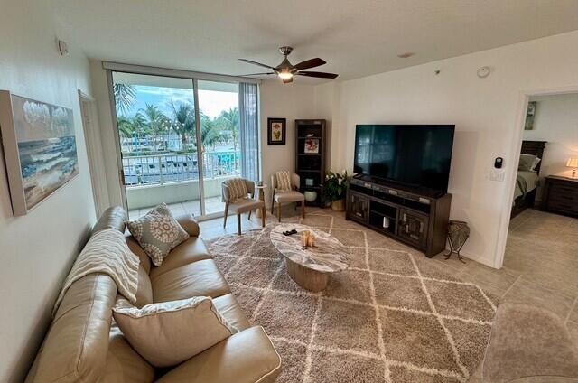 A living room features a leather sofa, a large television, and a balcony with water views — 625 Casa Loma Boulevard # 304, Boynton Beach FL 33435, BOYNTON BEACH, FL