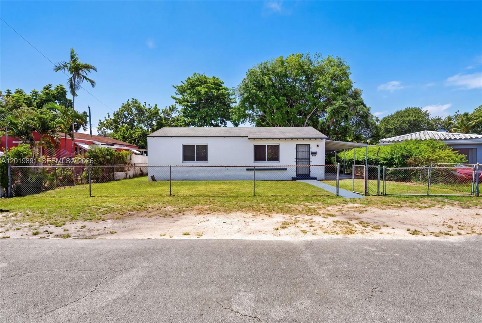 A single-story white house with a chain-link fence sits behind a paved road — 280 NW 101st St, Miami FL 33150, MIAMI, FL