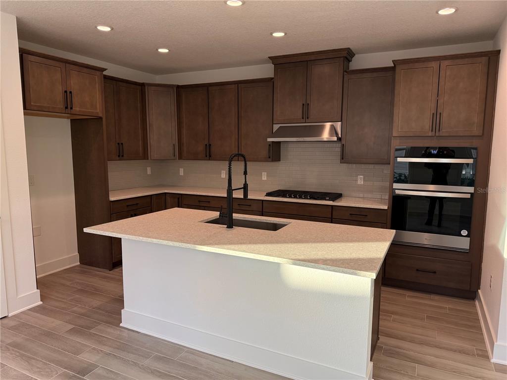 A modern kitchen features dark wood cabinets, a central island with a sink, and stainless appliances — 6 MULBERRY ROAD, PALM COAST, FL