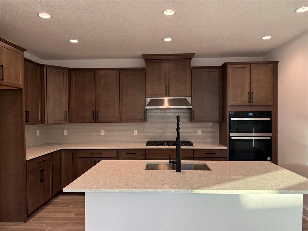 A modern kitchen features dark wood cabinets, light countertops, a center island, and stainless appliances — 6 MULBERRY ROAD, PALM COAST, FL