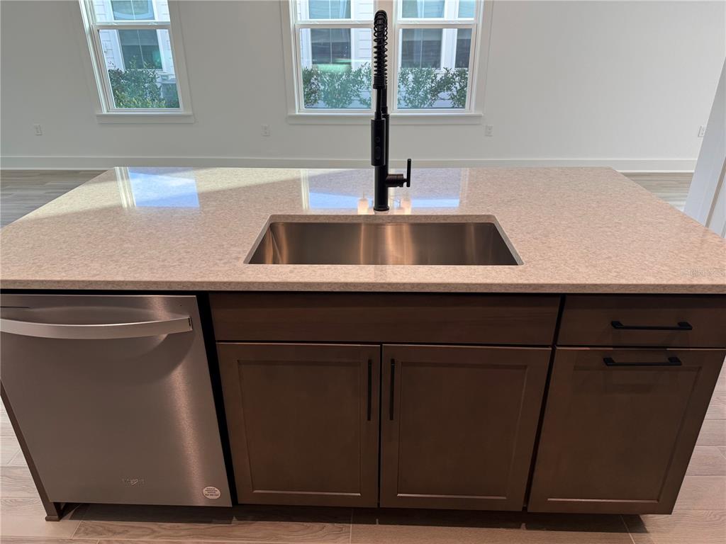 A kitchen island features a stainless steel sink, a black faucet, and dark wood cabinetry — 6 MULBERRY ROAD, PALM COAST, FL