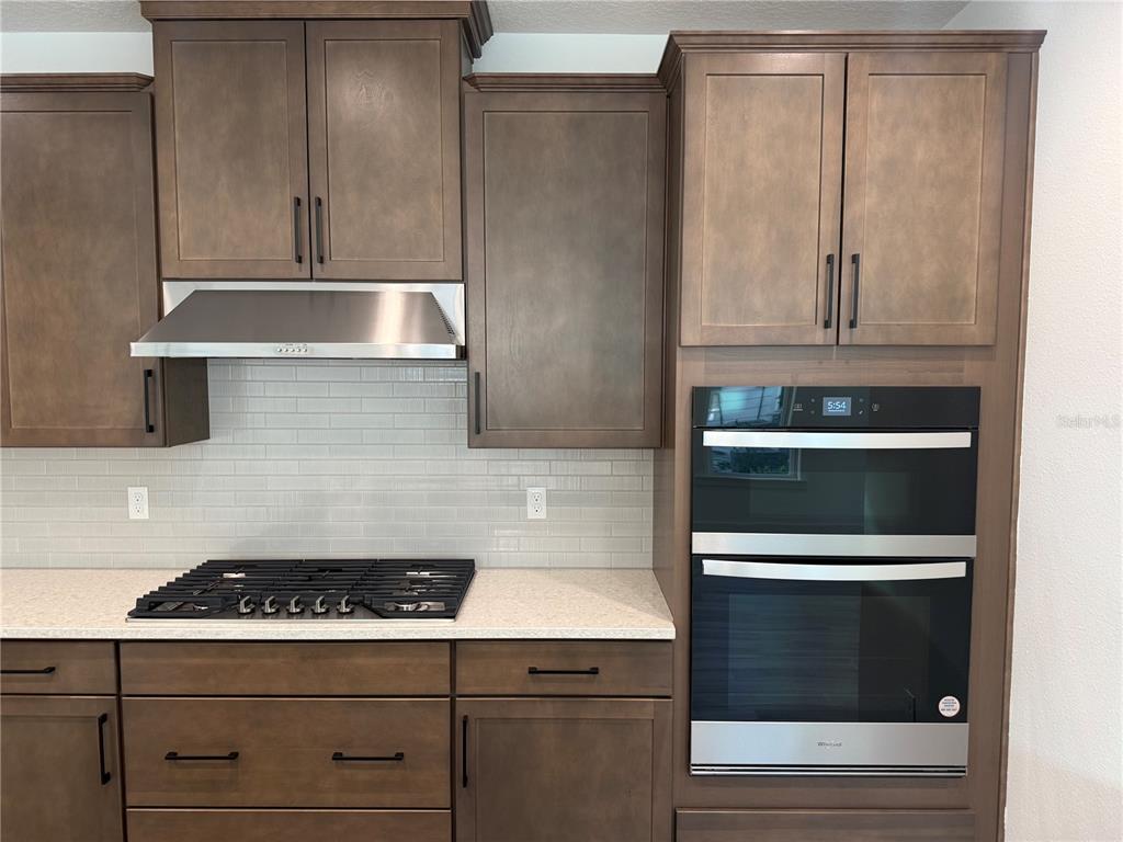 A kitchen features dark wood cabinets, stainless steel appliances, a gas cooktop, and light countertops — 6 MULBERRY ROAD, PALM COAST, FL