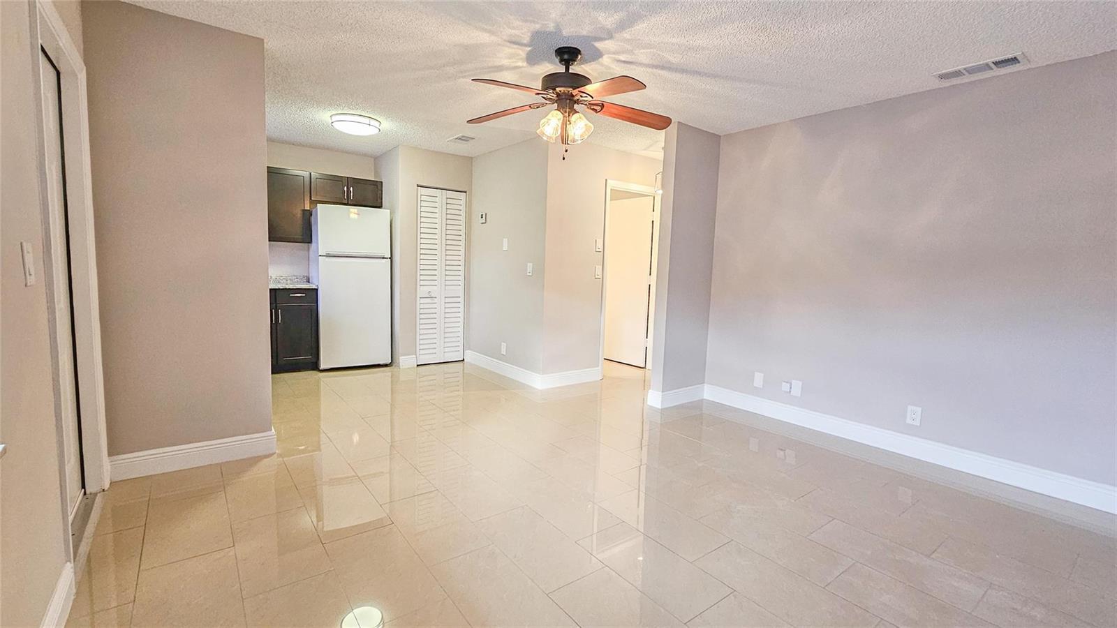 An open-concept living area features light-colored tile flooring, a ceiling fan, and an adjacent kitchen — 416 Lakeside Drive # 129, Margate FL 33063, MARGATE, FL