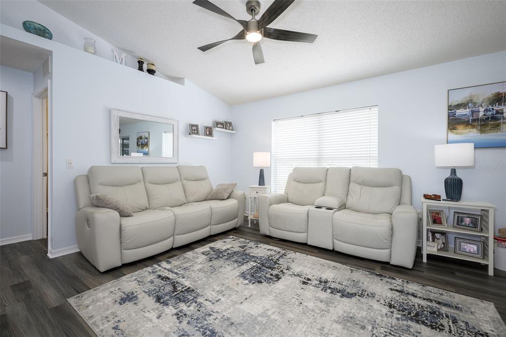 A living room features light blue walls, two white leather sofas, and a patterned rug — 6 SPIVEYS COURT, ORMOND BEACH, FL