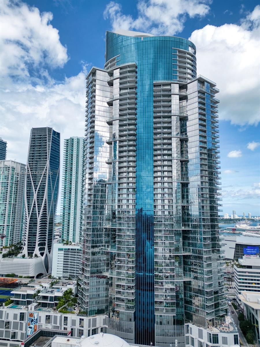 An aerial view shows a tall, modern glass skyscraper with balconies in a city skyline — 851 NE 1st Ave # 806, Miami FL 33132, MIAMI, FL