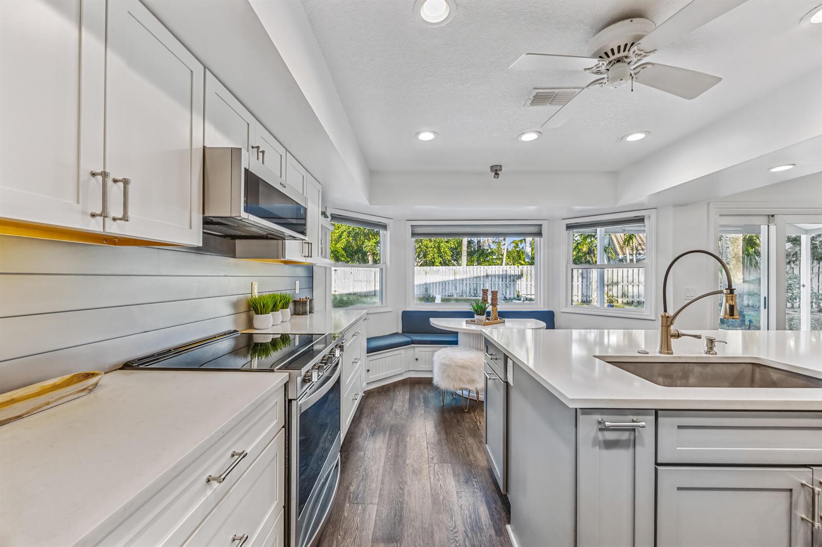 A kitchen features white cabinetry, a gray island, stainless steel appliances, and a breakfast nook — INDIALANTIC, FL