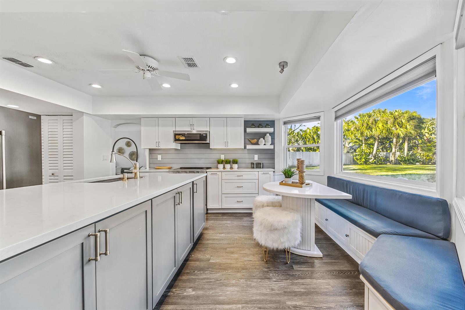A kitchen features a large island, gray cabinetry, and a built-in breakfast nook with seating — INDIALANTIC, FL