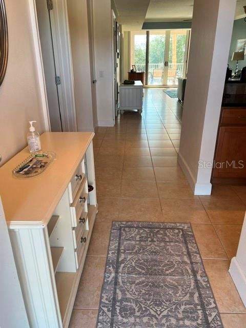 A tiled hallway leads past a white cabinet toward a bright room with sliding doors — 102 YACHT HARBOR DRIVE UNIT 264, PALM COAST, FL