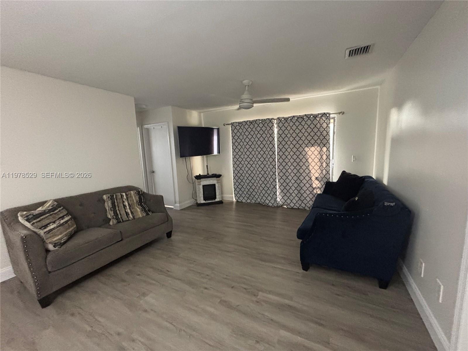 A living room features light wood-look flooring, a gray sofa, a blue sofa, and a television — 3615 NW 94th Ave # 8F, Sunrise FL 33351, SUNRISE, FL