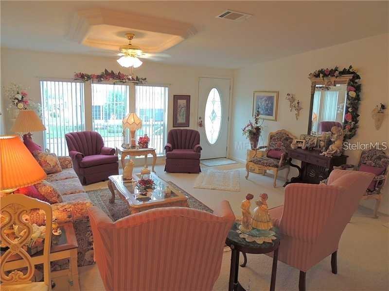 A living room features a coffered ceiling, vertical blinds, and various upholstered chairs and sofas — 37535 NEW HORIZONS BOULEVARD, ZEPHYRHILLS, FL