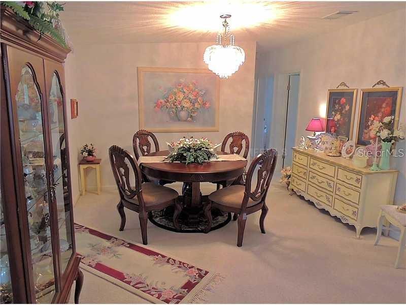 A dining room features a round wooden table, four chairs, a hutch, and a sideboard — 37535 NEW HORIZONS BOULEVARD, ZEPHYRHILLS, FL