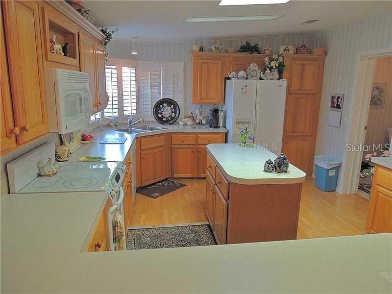 A kitchen with wood cabinets, white appliances, a central island, and light-colored countertops — 37535 NEW HORIZONS BOULEVARD, ZEPHYRHILLS, FL