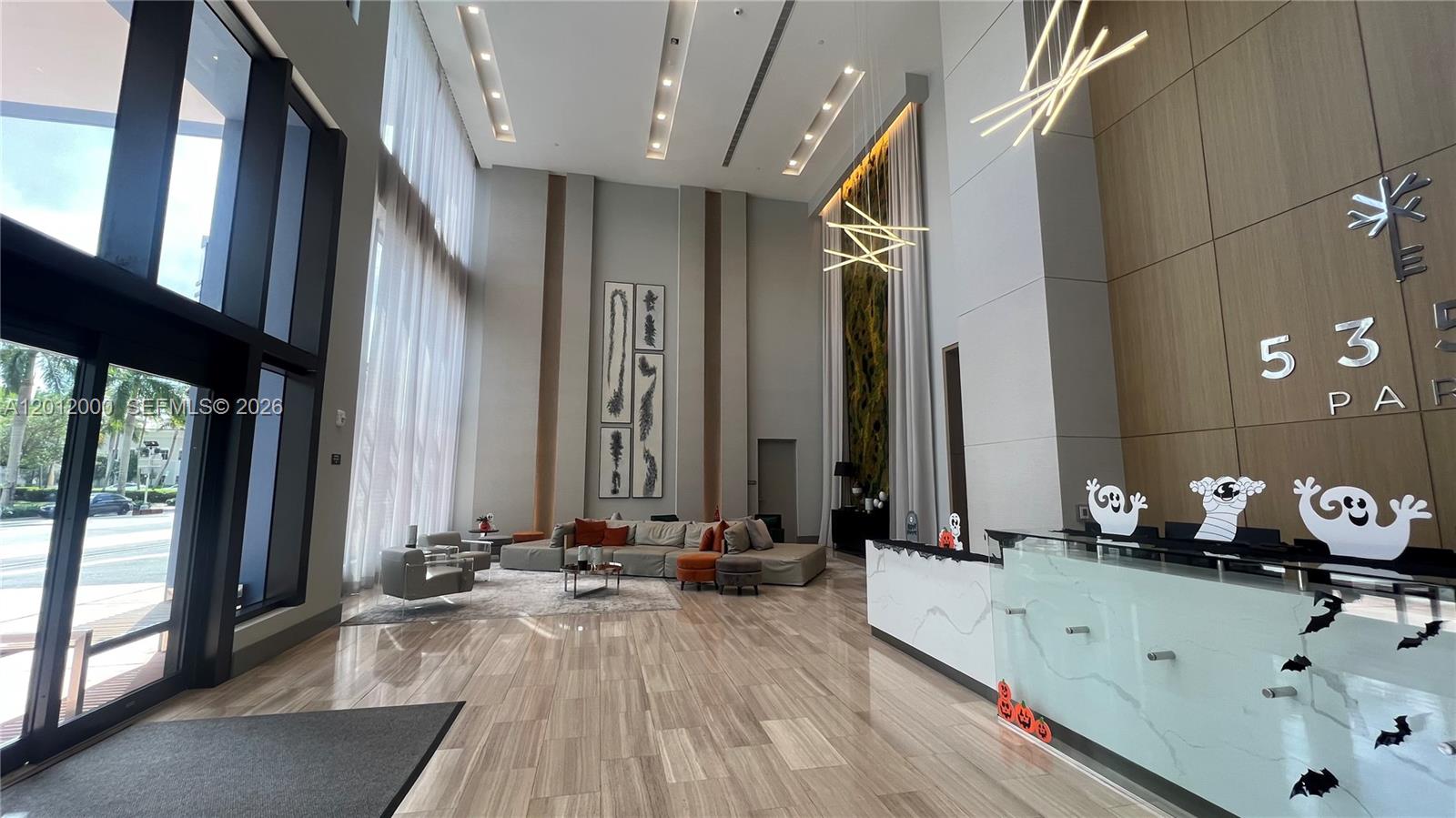 A modern lobby features high ceilings, a reception desk, and a seating area with sofas — 5350 NW 84th Ave # 1605, Doral FL 33166, DORAL, FL