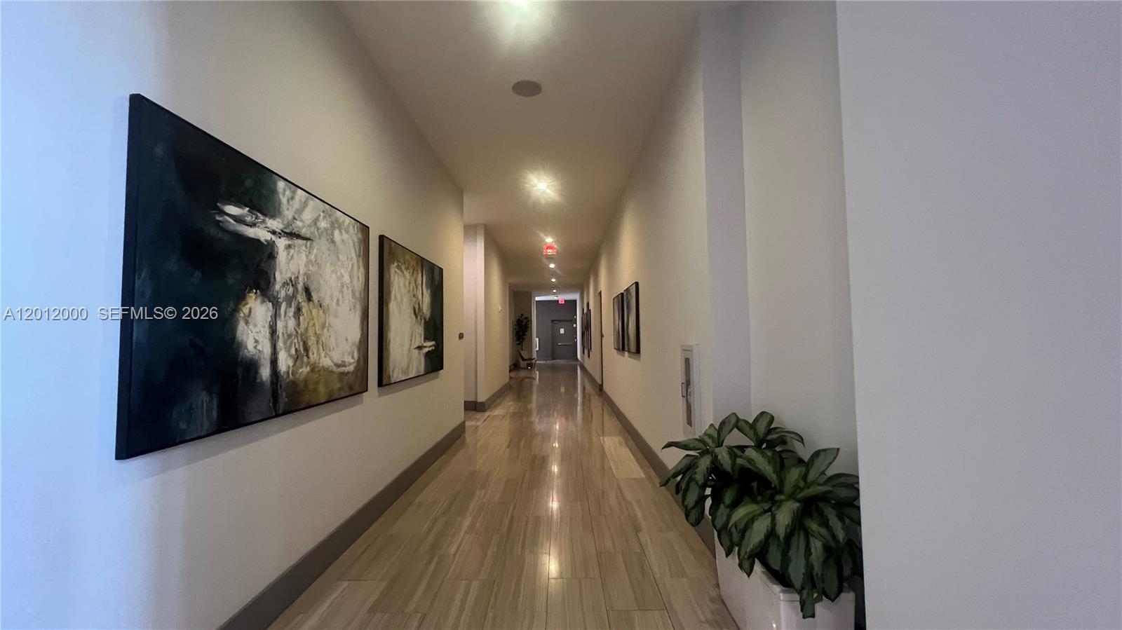 A long, narrow hallway features light-colored tile flooring, recessed lighting, and abstract wall art — 5350 NW 84th Ave # 1605, Doral FL 33166, DORAL, FL