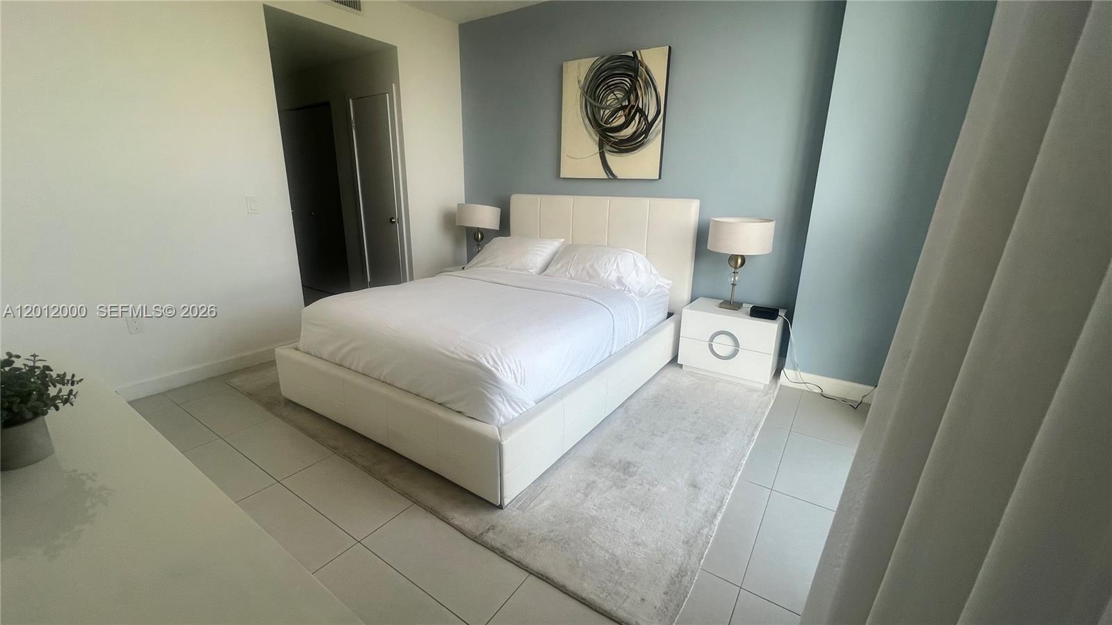 A bedroom features a white bed, a blue accent wall, and a light-colored area rug — 5350 NW 84th Ave # 1605, Doral FL 33166, DORAL, FL
