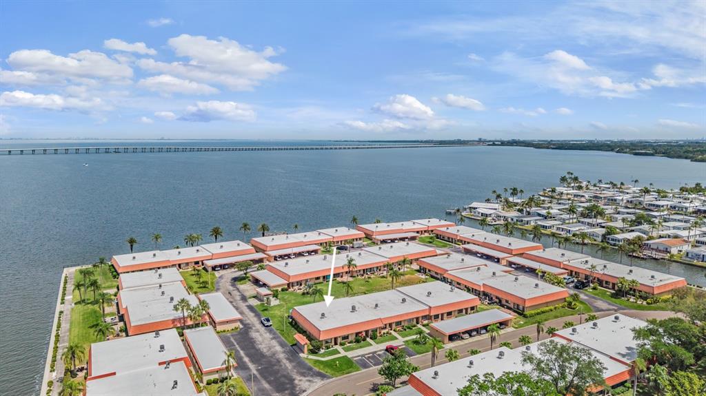 An aerial view shows a waterfront residential complex with a white arrow pointing to a unit — 19029 US HIGHWAY 19 N UNIT 27A, CLEARWATER, FL