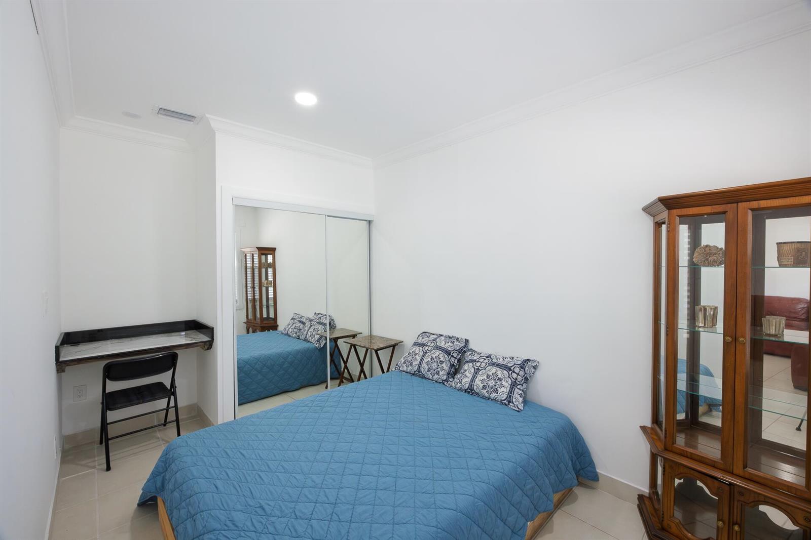 A bedroom features a blue bed, a mirrored closet, a wall-mounted desk, and a wooden cabinet — 4591 Purdy Lane # 1, West Palm Beach FL 33415, WEST PALM BEACH, FL