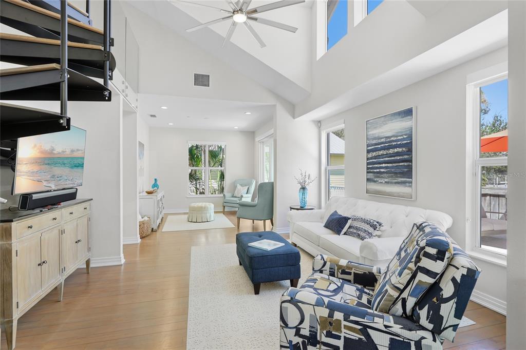 A bright living room features a spiral staircase, vaulted ceilings, and blue-toned furniture — 392 FIREHOUSE LANE, LONGBOAT KEY, FL