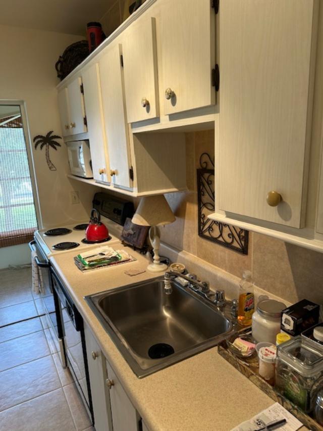 A kitchen features light-colored cabinets, a stainless steel sink, a stove, and a tile backsplash — 550 NW 78th Avenue # 204, Margate FL 33063, MARGATE, FL
