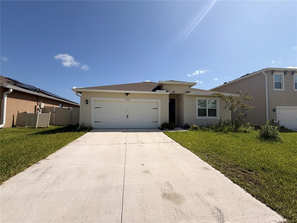 A single-story house with a white garage, beige stucco exterior, and a concrete driveway — 2250 HIDDEN PALM DRIVE, SANFORD, FL
