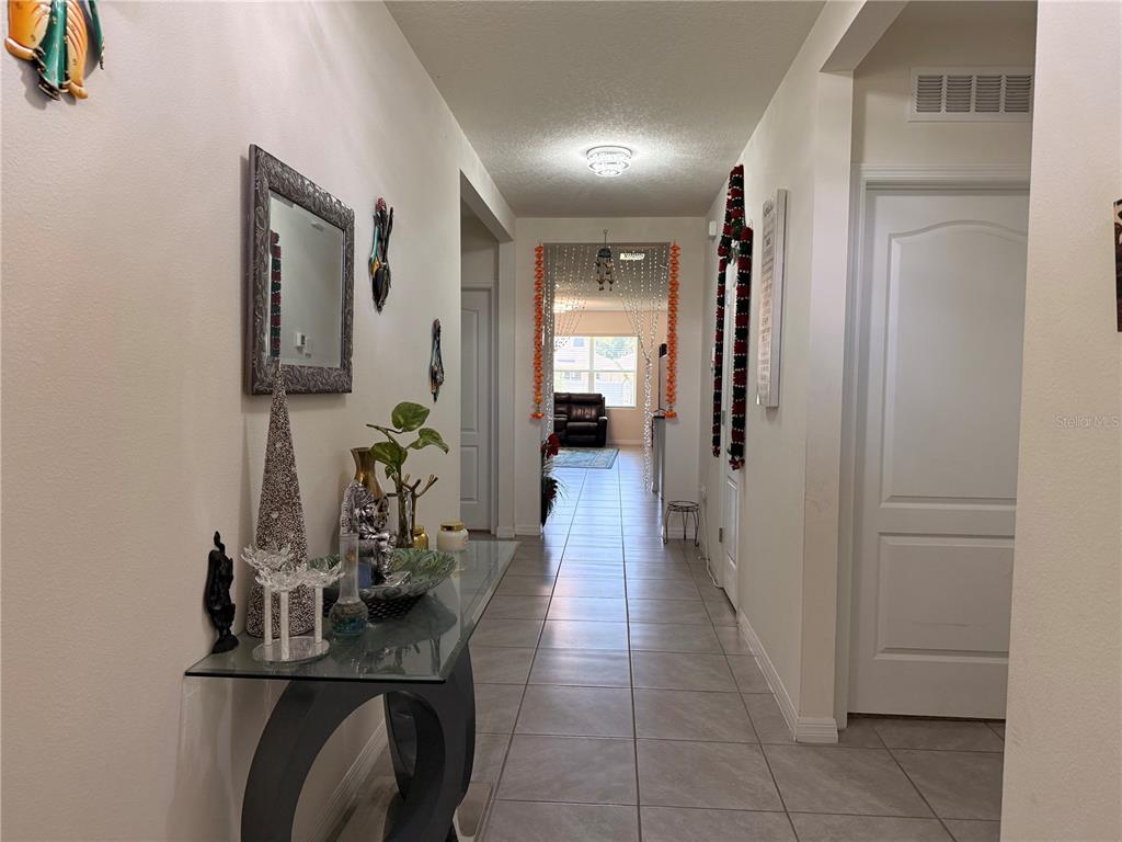 A tiled hallway features a glass console table, wall mirror, and a view into a living area — 2250 HIDDEN PALM DRIVE, SANFORD, FL