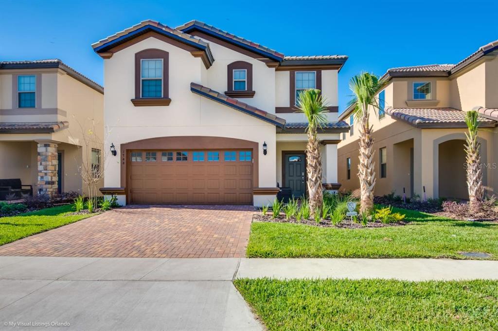 A two-story suburban house with a tan stucco exterior, brown trim, and a paved driveway — 1744 LIMA AVENUE, KISSIMMEE, FL