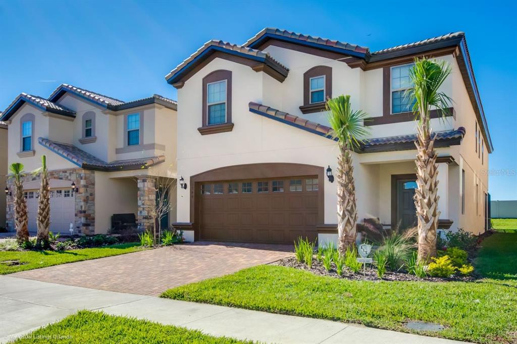 Two two-story suburban houses with stucco exteriors, tile roofs, and paved driveways under a blue sky — 1744 LIMA AVENUE, KISSIMMEE, FL