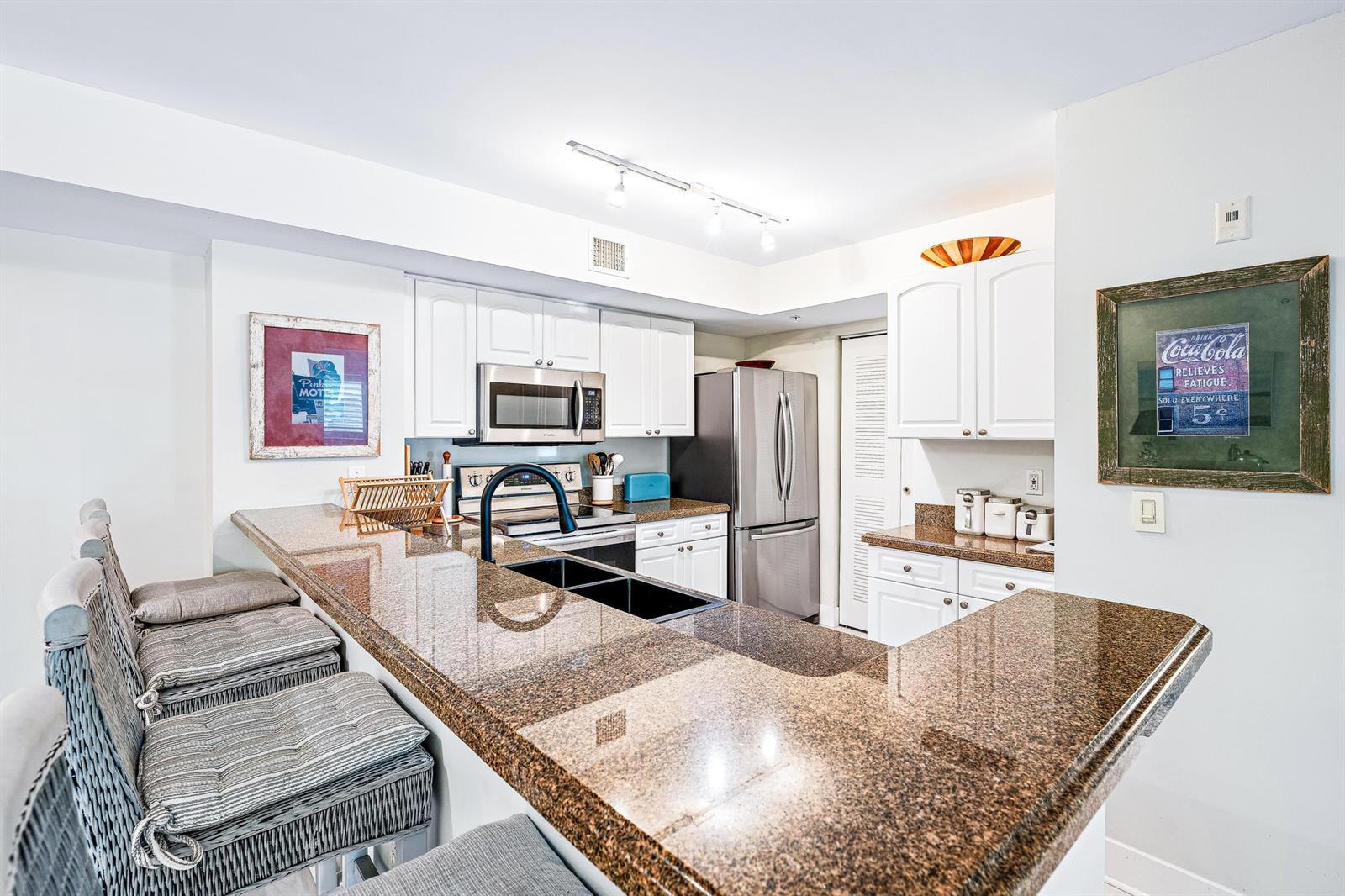 A kitchen features granite countertops, white cabinetry, stainless steel appliances, and a breakfast bar — 242 Village Boulevard # 2109, Tequesta FL 33469, TEQUESTA, FL