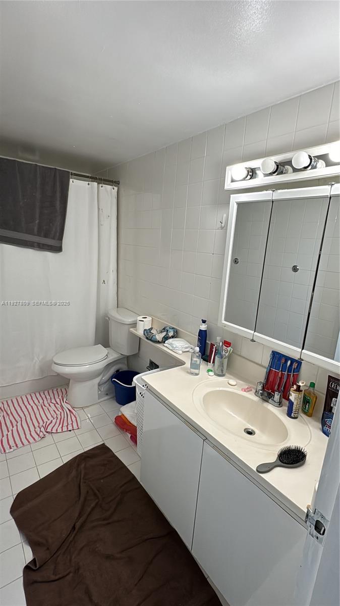 A bathroom features a white vanity, a toilet, a shower with a curtain, and tiled walls — 905 Brickell Bay Dr # B, Miami FL 33131, MIAMI, FL