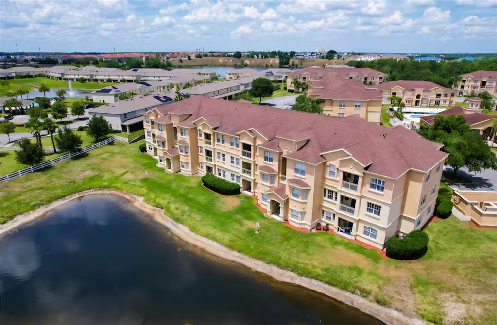 An aerial view shows a multi-story apartment building situated next to a small pond — 818 TERRACE RIDGE CIRCLE UNIT 818, DAVENPORT, FL