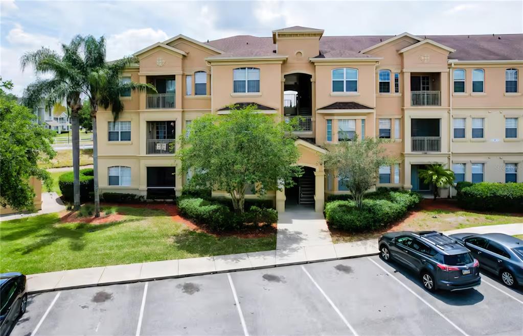 An exterior view of a three-story apartment building with a parking lot in front — 818 TERRACE RIDGE CIRCLE UNIT 818, DAVENPORT, FL