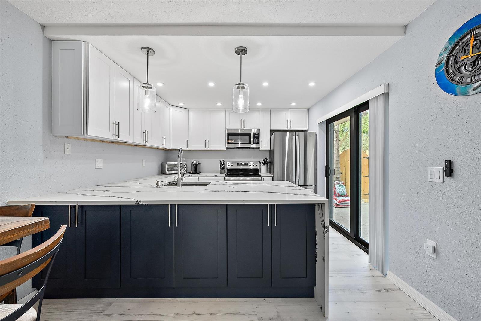 A kitchen features white upper cabinets, dark blue lower cabinets, and a marble-patterned island countertop — 2902 29th Court, Jupiter FL 33477, JUPITER, FL