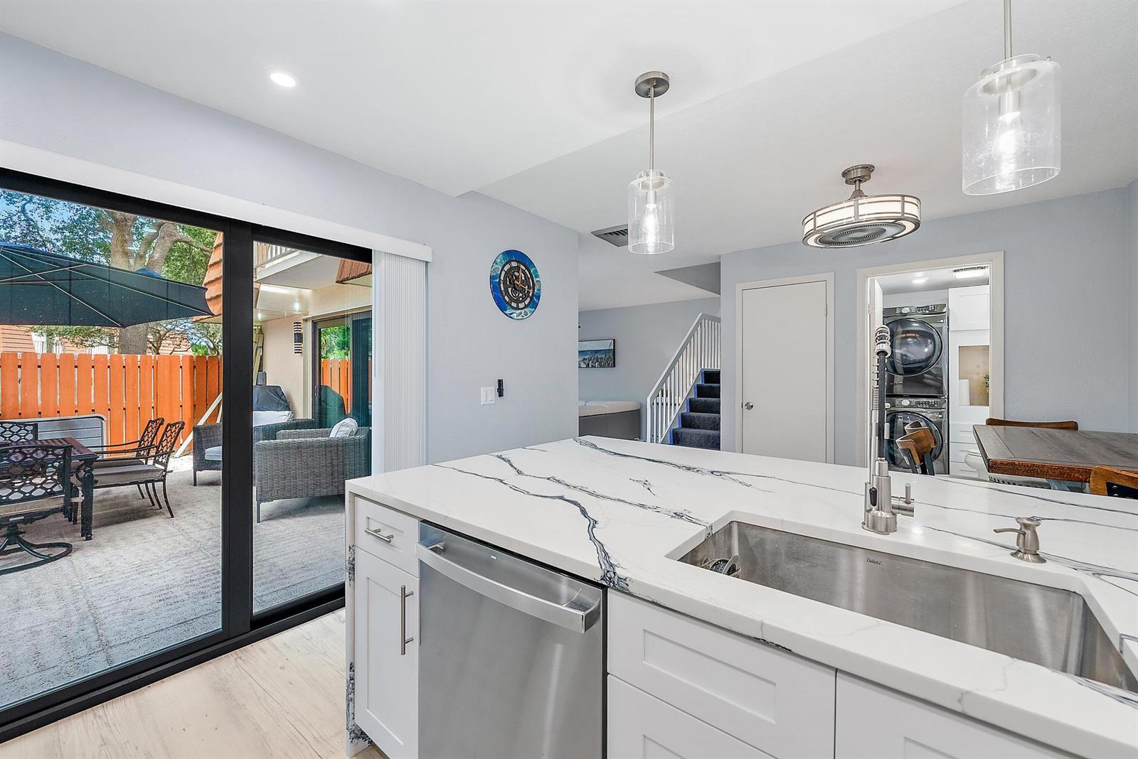 A kitchen island with a marble countertop and stainless sink overlooks a patio through sliding doors — 2902 29th Court, Jupiter FL 33477, JUPITER, FL