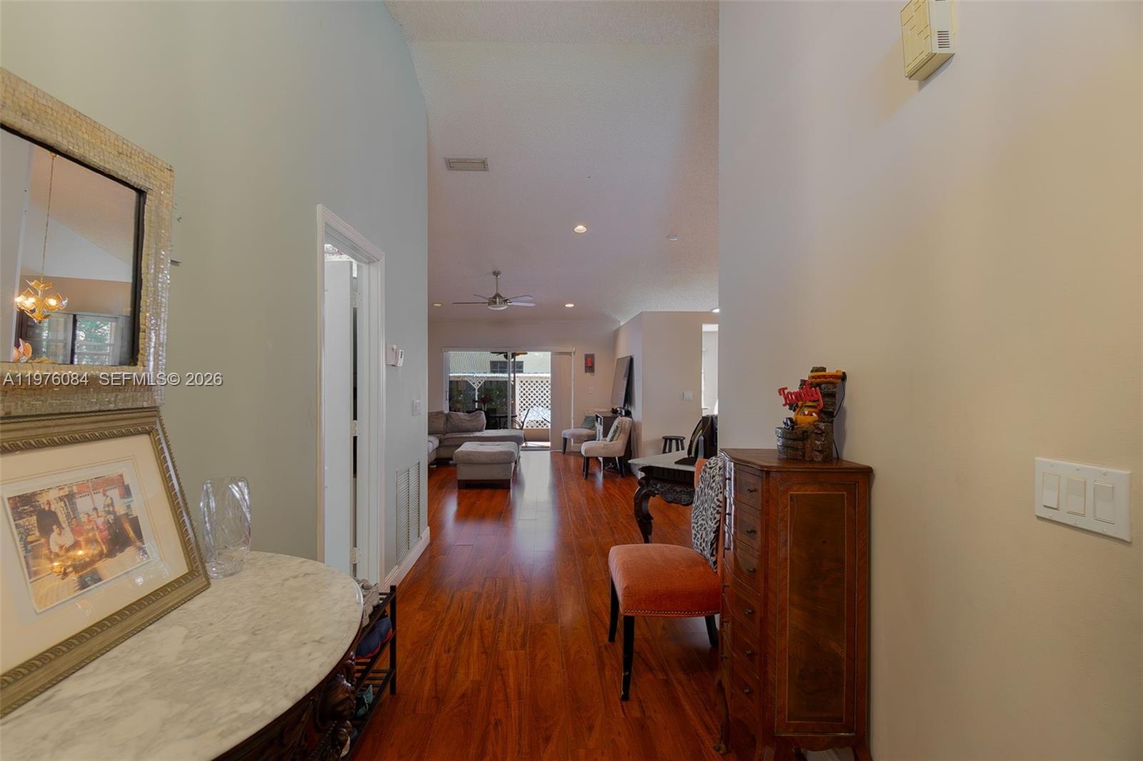 A hallway with hardwood floors leads into a living area with a sliding glass door — 6618 Skipper Ter, Margate FL 33063, MARGATE, FL