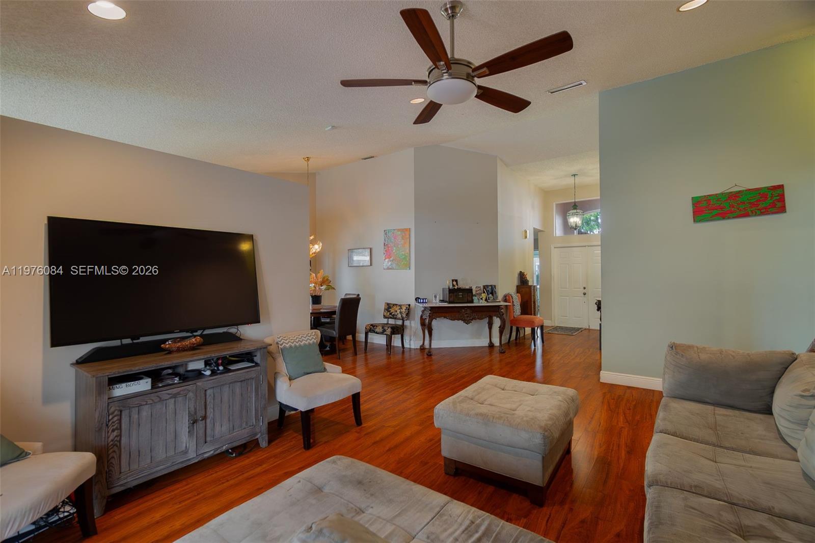 A living room features hardwood floors, a ceiling fan, and a large wall-mounted television — 6618 Skipper Ter, Margate FL 33063, MARGATE, FL