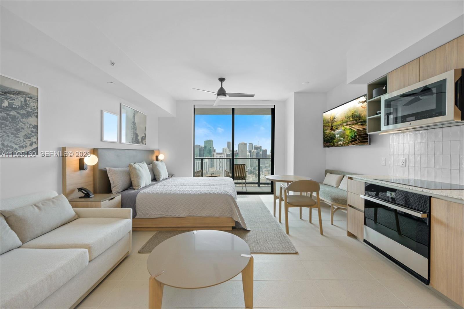 A studio apartment features a bed, kitchenette, seating area, and a balcony with city views — 159 NE 6th St # 3810, Miami FL 33132, MIAMI, FL