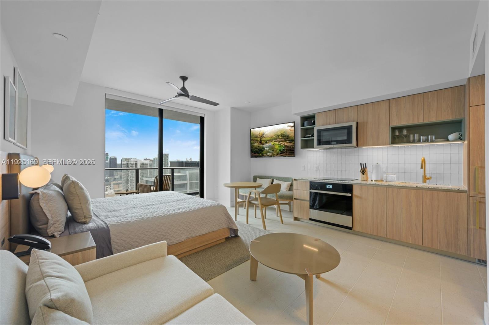 A studio apartment features a bed, kitchenette, dining area, and floor-to-ceiling windows with city views — 159 NE 6th St # 3810, Miami FL 33132, MIAMI, FL