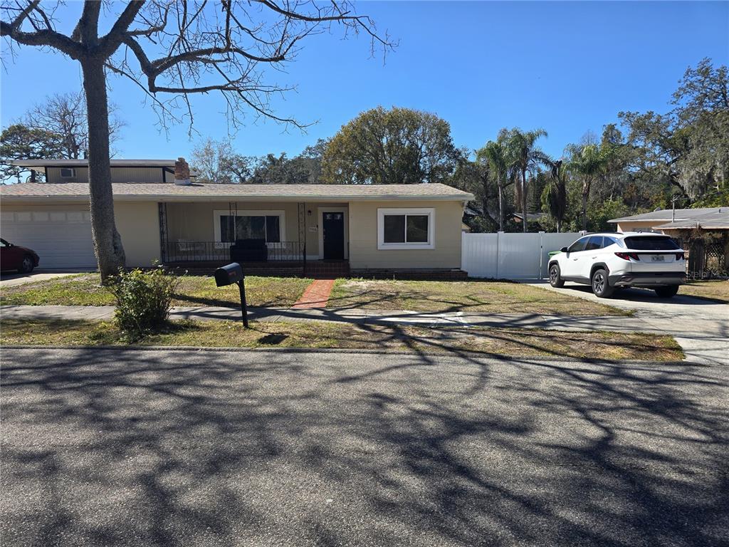 A single-story house with a beige exterior, a front porch, and a white fence — 9306 FOREST HILLS DRIVE, TAMPA, FL
