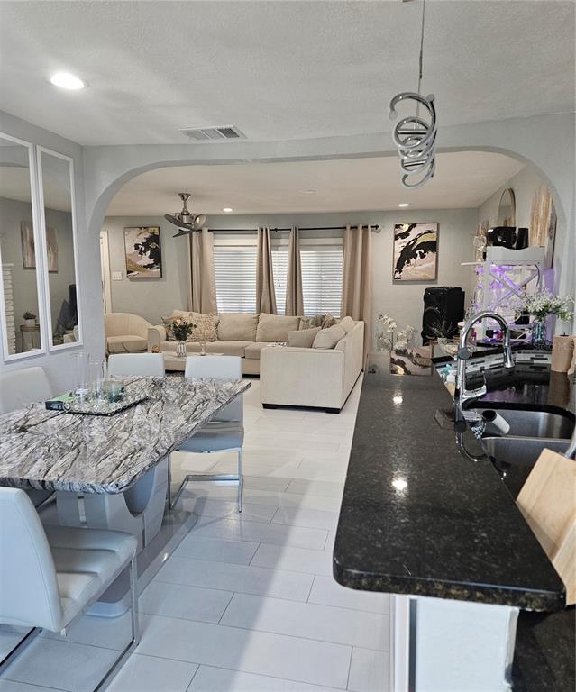 A dining area with a marble table overlooks a living room with a sectional sofa — 9306 FOREST HILLS DRIVE, TAMPA, FL